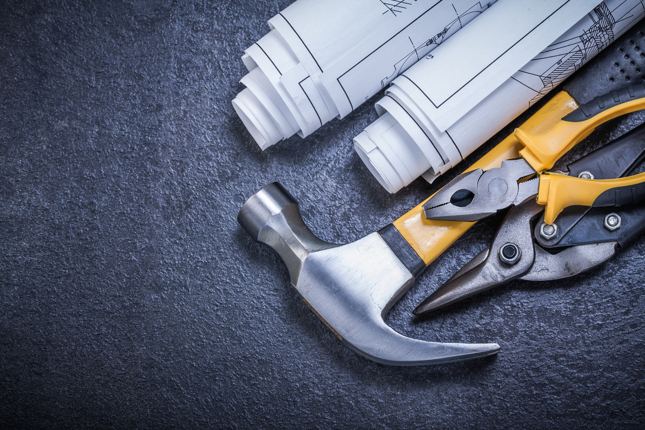 Rolled blueprints steel cutter pliers claw hammer on black backg design-build project